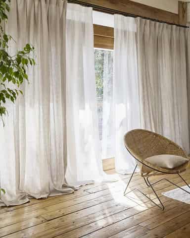 Liveleff sfeerbeeld met gordijnen bij openslaande deuren Gordijnen langs openslaande deuren, met een stoel en planten in het interieur