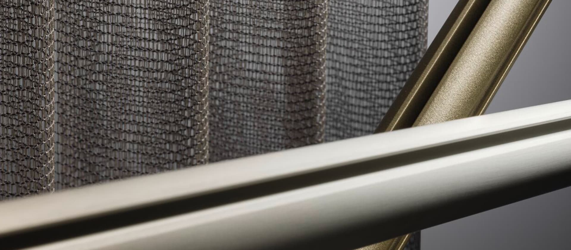 Gordijndetail met gekruiste zilver- en goudkleurige SLIDE-profielen Gordijndetail met gekruiste zilver- en goudkleurige SLIDE-profielen.