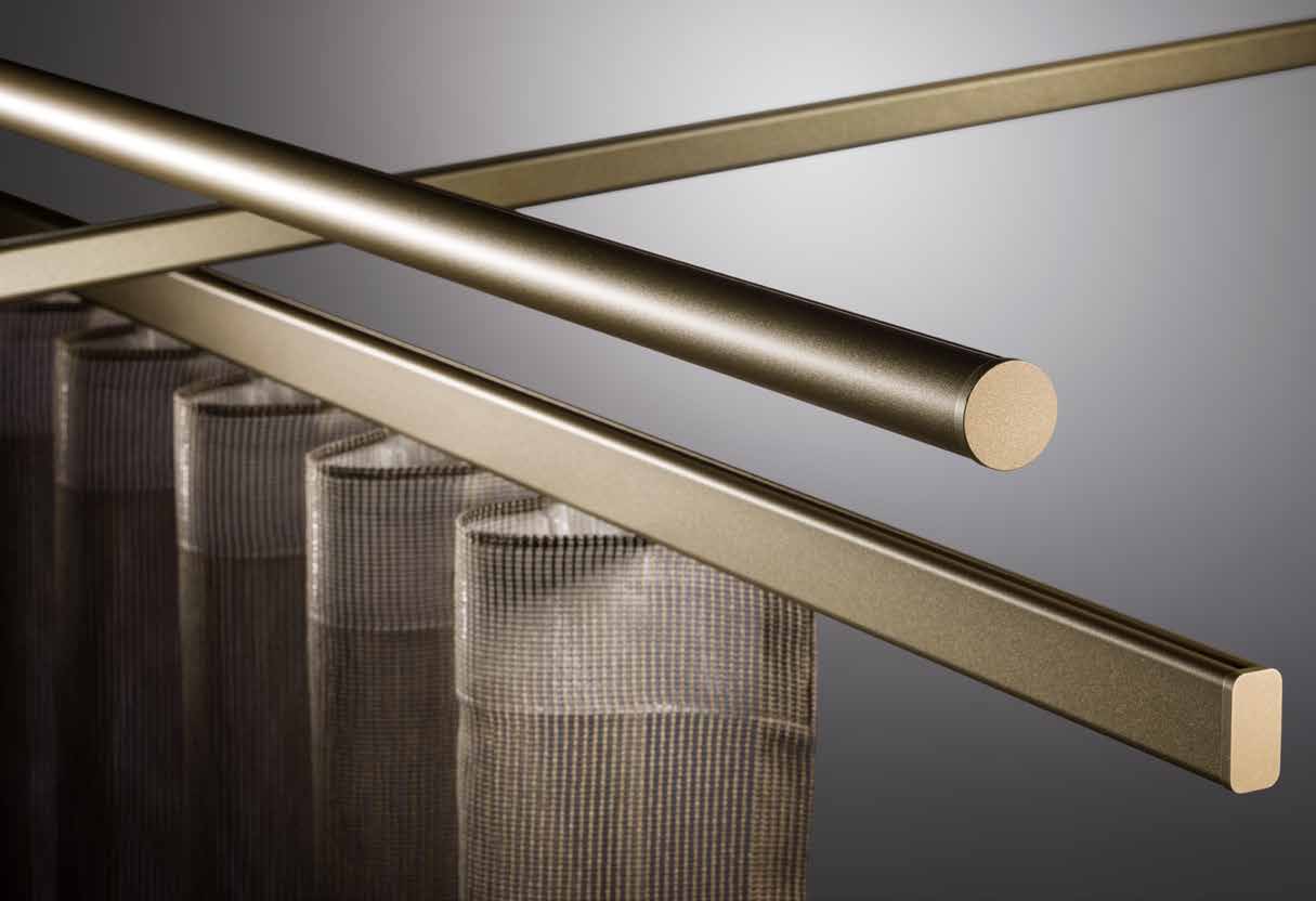 Goudkleurige ronde en ovale SLIDE-profielen met eindkappen boven gordijnen Goudkleurige ronde en ovale SLIDE-profielen met eindkappen boven gordijnen.