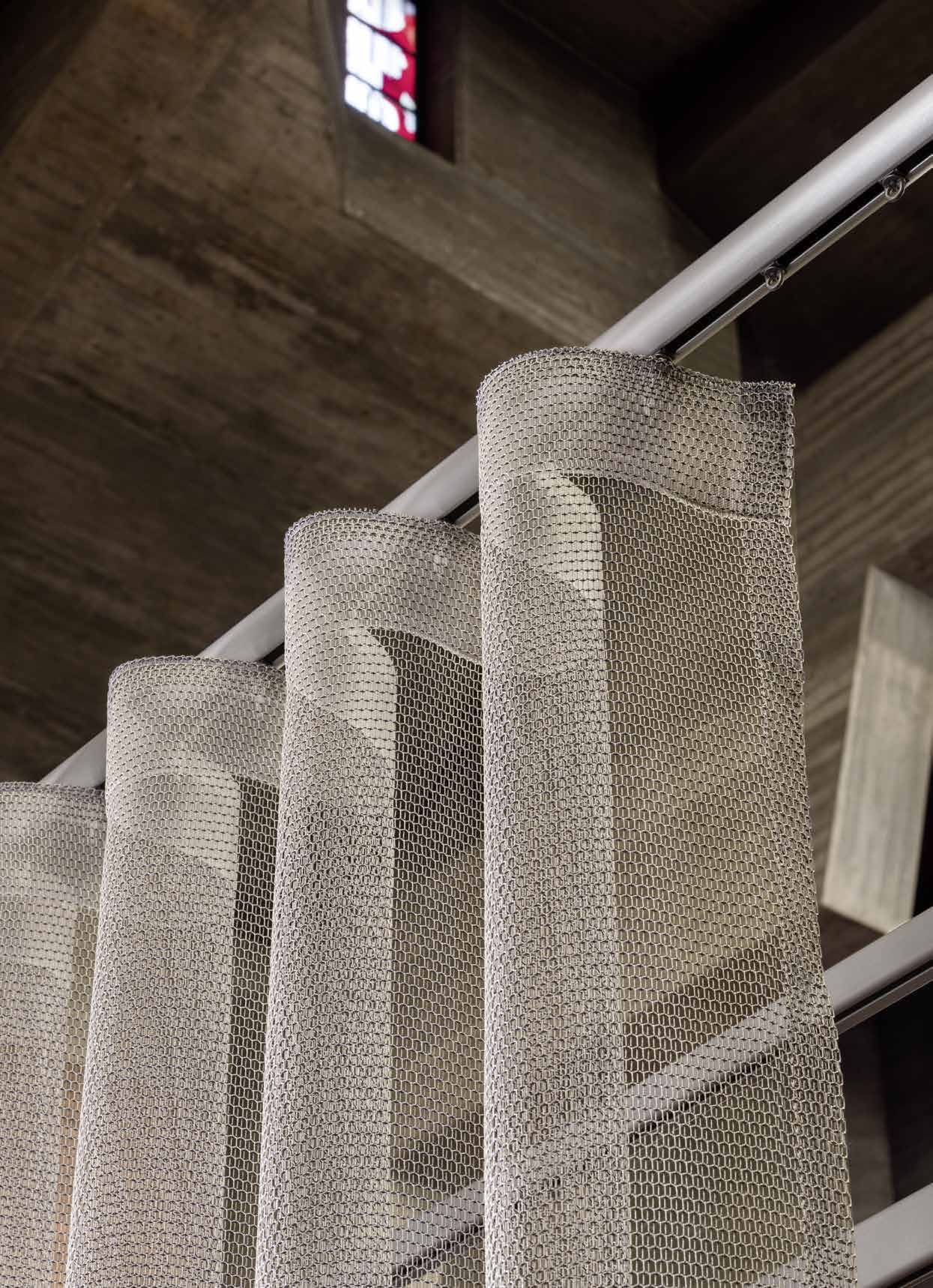 SLIDE-rail boven lichtdoorlatende Wave-gordijnen, van onderen gezien naast een houten wand SLIDE-rail boven lichtdoorlatende Wave-gordijnen, van onderen gezien naast een houten wand.