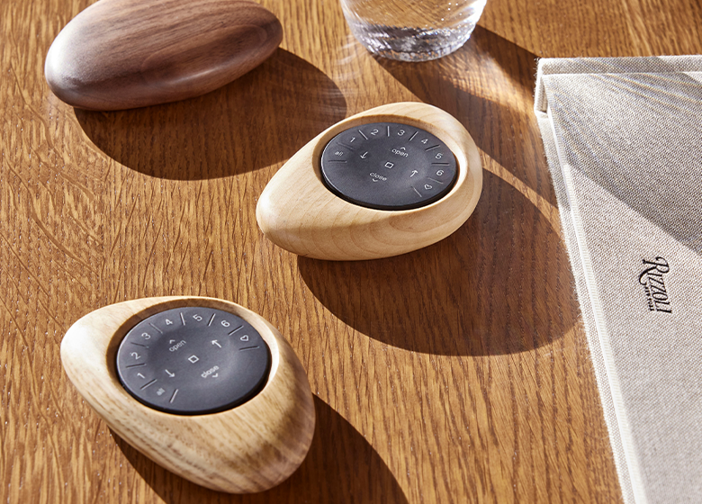 PowerView Remotes in houten Pebble-hulzen op een tafel PowerView Remotes in houten Pebble-hulzen op een tafel.