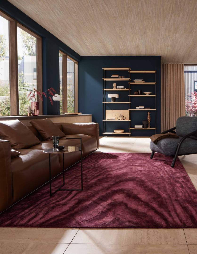 JAB ANSTOETZ ICONS CARDUUS — Piero Lissoni JAB ANSTOETZ ICONS CARDUUS 7677/613 van Piero Lissoni, een bordeauxrood vloerkleed met organisch reliëf in een woonkamer.