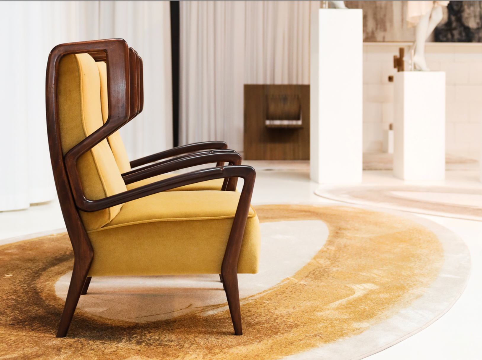 Interieur met een geel beklede houten fauteuil en een ovaal Mart Visser BRUSH vloerkleed in warme geel- en bruintinten.